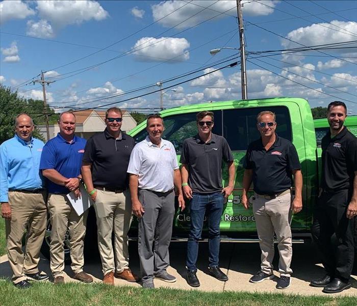 image of SERVPRO employees/owners in front of a SERVPRO truck smiling for a picture
